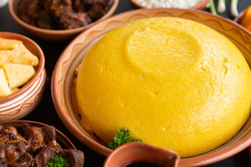 Homemade Romanian Food with polenta, meat, cheese and vegetables. Delicious corn porridge in clay dishes. Mamaliga or polenta, a traditional dish in Moldova, Hungary and Ukrainian cuisine.
