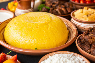 Homemade Romanian Food with polenta, meat, cheese and vegetables. Delicious corn porridge in clay dishes. Mamaliga or polenta, a traditional dish in Moldova, Hungary and Ukrainian cuisine.
