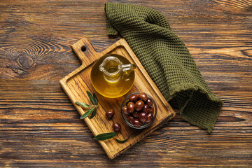 Board with decanter of fresh oil and olives on wooden background