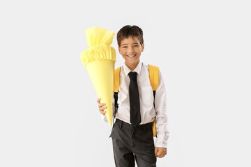Little boy with yellow school cone on light background