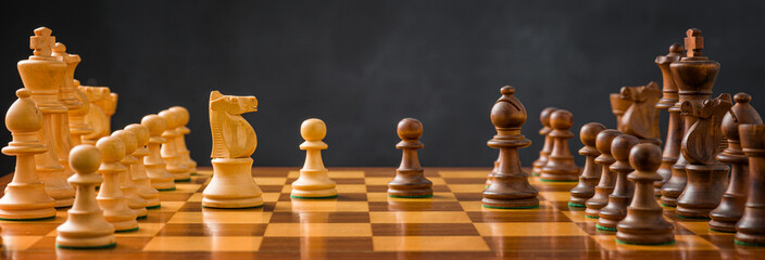 Chess pieces on a chessboard with a dark background - obrazy, fototapety, plakaty