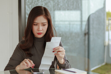 young woman look at pay bill holding ache at work. Tired woman employee looking at report on paper...