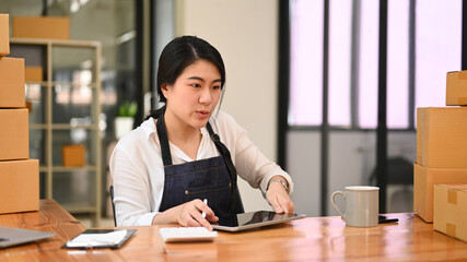 Start up small business owner checking online order on digital tablet, working at her home office