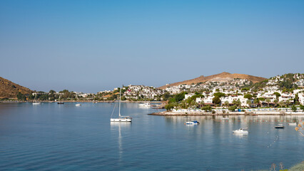 Fototapeta na wymiar View of Bodrum Beach, Aegean sea, traditional white houses, flowers, marina, sailing boats, yachts in Bodrum town Turkey. Front view