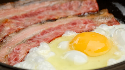 Frying fried eggs with Bacon in hot pan. Family Breakfast concept