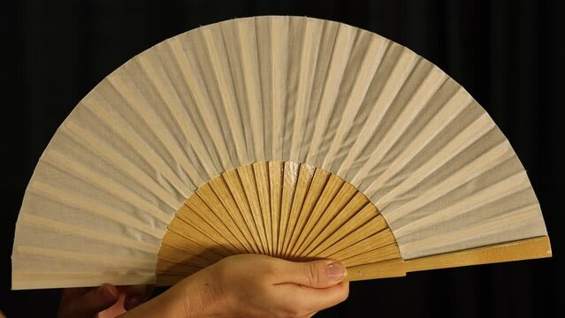 Close up of hands opening and closing flamenco fan, abanico, on stage. Static