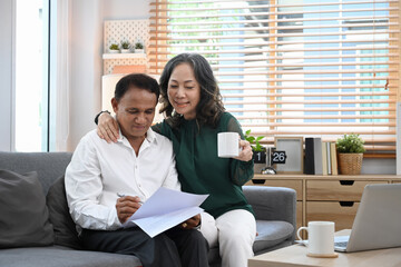 Fototapeta premium Happy elderly couple make payment on internet banking service, paying domestic bills online on laptop