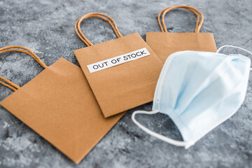 Out of Stock text on top of shopping bag with surgical mask, supply chain shortages and delays...