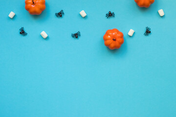 Halloween background with pumpkins, marshmallows and spiders on a blue background.