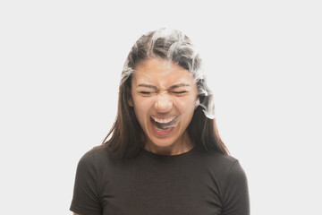 Shouting young girl with dark hair releases smoke from the mouth isolated over white background. Concept of mental health, art, human emotions