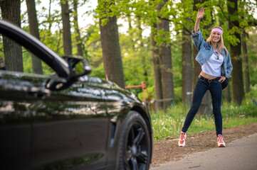 Blonde young woman stopping the care on the countryside road