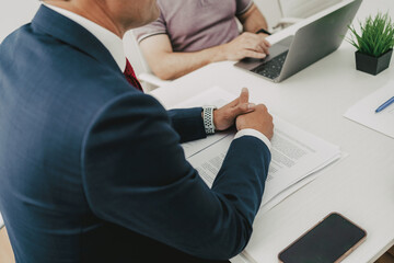 businessman in a meeting brainstorming with other office workers at a table. Closed picture of his hands.