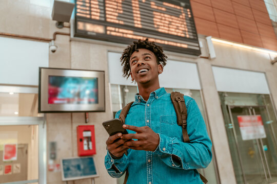 Guy with smartphone looking up at train station