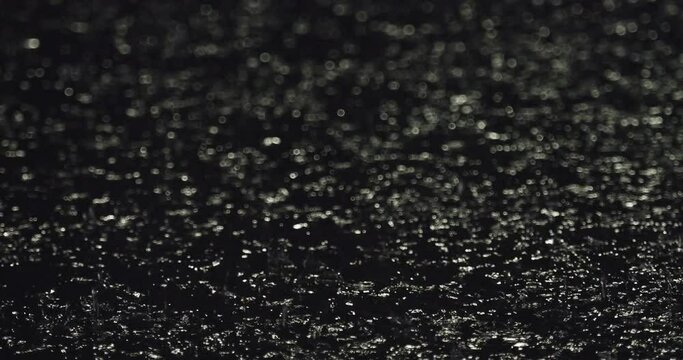 Closeup shot of heavy rain splashing in a puddle at night
