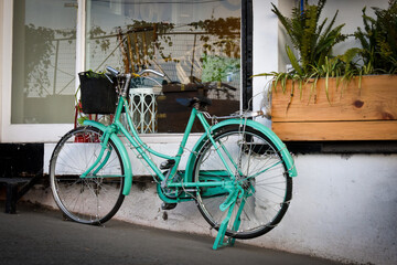 Fototapeta na wymiar January 1st 2020 Mussoorie Uttarakhand India. A light green antique decorative ladies bicycle with basket outside a cafe for decorative purposes.