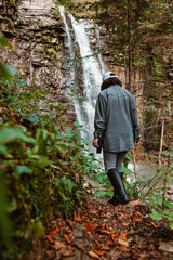 Naklejka na ściany i meble woman hiker enjoying view of waterfall