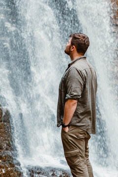 young strong man hiker looking the waterfall