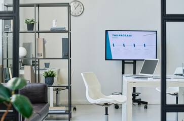 Modern office room with table in the middle and big monitor for meeting and presentation