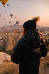 Girl observing the horizon with background of hot air balloons
