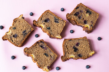 Sliced banana bread with blueberries on yellow background.
