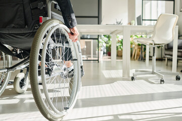 Close-up of office worker with disability sitting in wheelchair while working at office