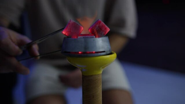 A man puts coals on a hookah bowl. Preparation for smoking
