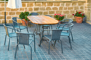 Terrace set with a wooden table and seven metal chairs with a sunshade