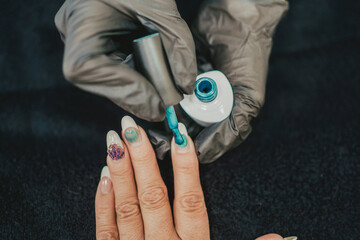 a professional painting a woman's nails in her beauty center. Close up of the hands