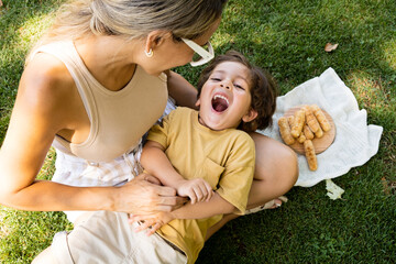 Mother and son enjoying and eating a Latin American snack called tequeños, funny expressions on their faces