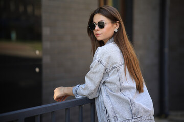 Close up portrait of a fashionable young woman in modern sunglasses over brick wall background. Street style. Beauty, fashion concept. Optics, eyewear.