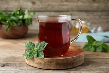 Cup of hot aromatic tea with mint on wooden table