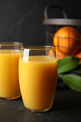 Glasses of orange juice on black table