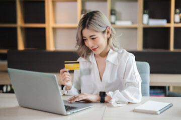 Young beautiful Asian woman smiling and happy, showing presenting credit card online shopping using with mobile phone app pay online copy space.