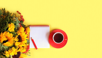 notebook with pencil, tea cup, autumn bouquet of sunflowers on yellow background. Tea party, fall season concept. copy space. flat lay