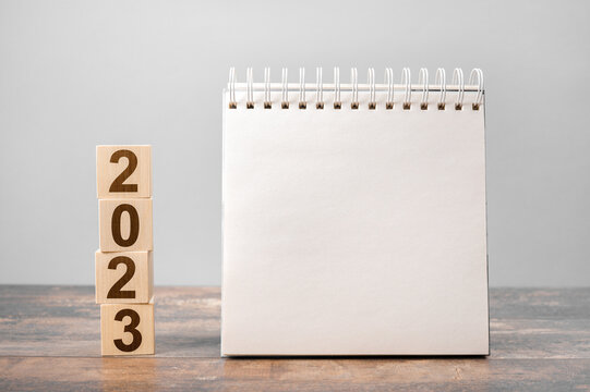 Mockup 2023 calendar. Text 2023 on wooden cubes. space for your text on notepad, mockup calendar. New Year. startup concept. Year 2023 and notepad