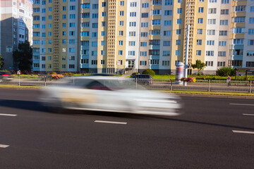 Blurred white car movement along the avenue at daytime.