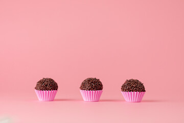 Brigadeiros de chocolate em fundo infinito rosa	
