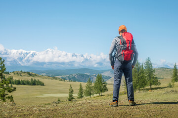 Fototapeta na wymiar Man traveling with backpack hiking in mountains. Man hiker looks on the beautiful landscape and thinks. Travel Lifestyle wanderlust adventure concept.