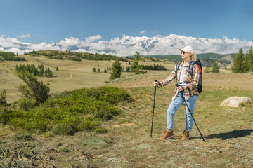  mature woman hiker with backpack using poles,  hiking in mountains.