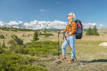 Fototapeta na wymiar Portrait of happy mature woman hiking in the mountains. Travel Lifestyle concept adventure summer vacations outdoor.