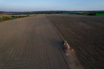 Fototapeta premium The tractor mills the field. Modern machinery in the farmer's field. Top view.