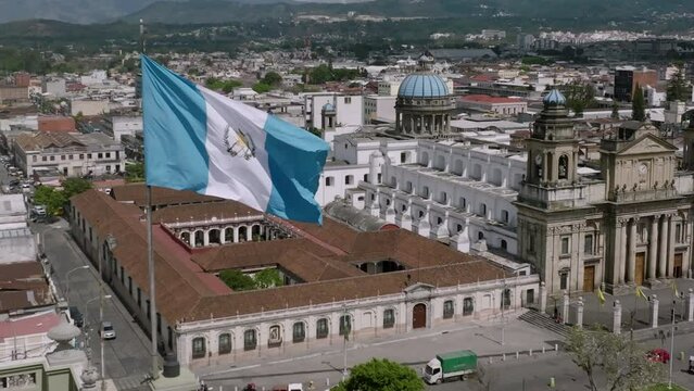 Slow motion aerial of the Guatemalan Flag in the air with the Metropolitan Cathedral of Santiago of Guatemala in the background in  Guatemala City, Guatemala