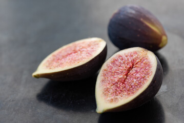 red sliced ​​fresh figs lie next to each other, against a gray background