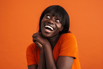 Portrait of smiling african woman touching chin over orange background