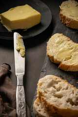 Low key food photography. Rustic bread with butter on dark background.