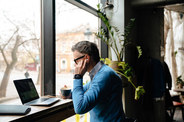 Adult man in blue sweater and glasses adjusting headphones