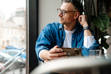 Adult handsome man in glasses looking out window