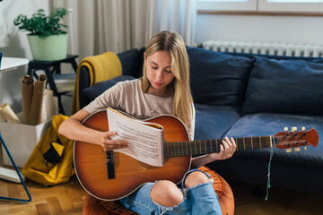 teenager girl playing acoustic guitar at her home