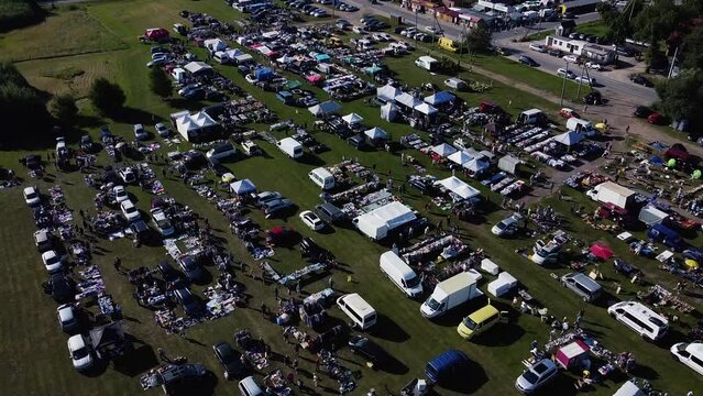 Aerial Cinematic car boot sale market shot. Large marketplace in the field in Europe.