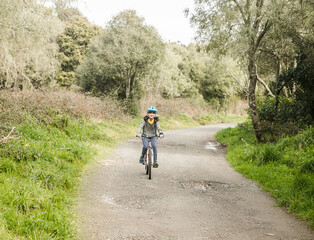 Obraz premium outdoor portrait of a child girl riding a bike, active lifestyle, reacreation leisure time on natural background